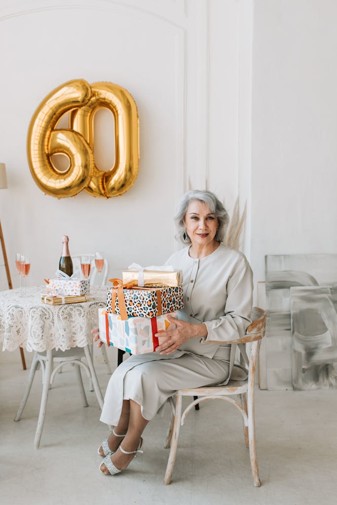 Home A sophisticated senior woman celebrates her 60th birthday with gifts and champagne in a stylish setting.