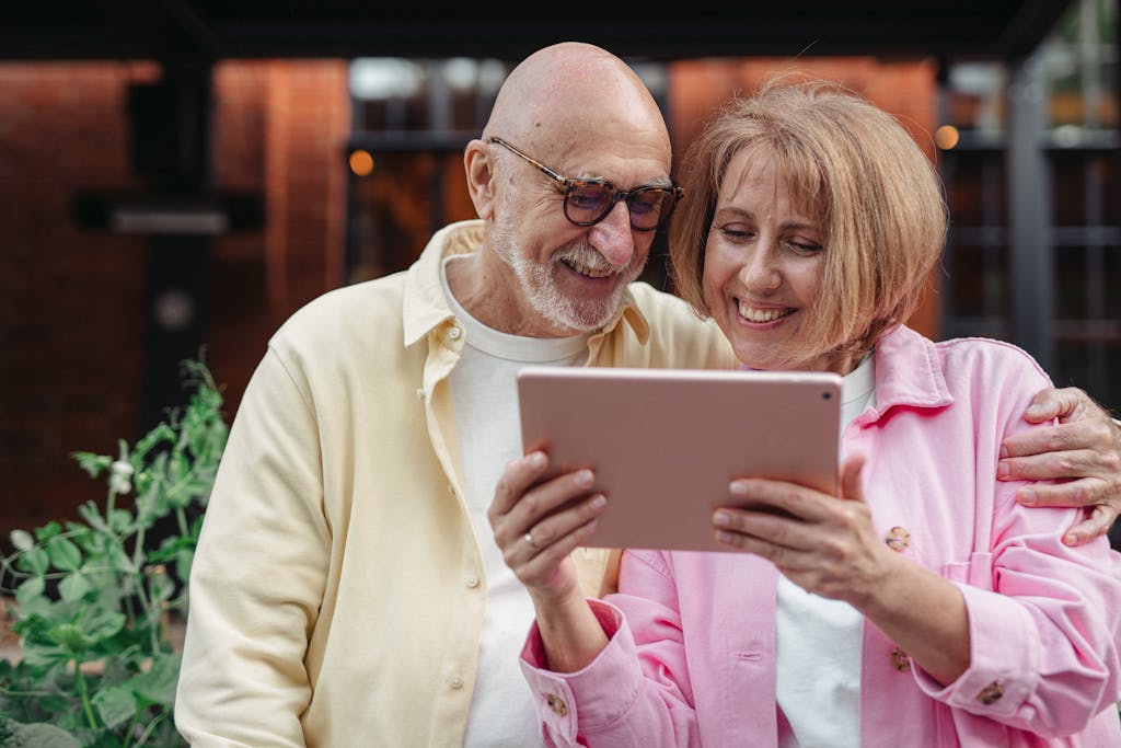 Home Happy senior couple using a tablet together, enjoying outdoor leisure time.